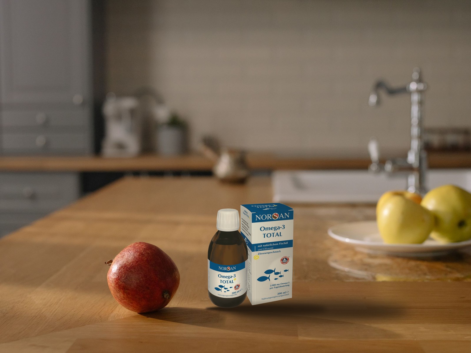NORSAN Omega-3 Total, Flasche und Karton auf einem Küchentisch aus Eichenholz